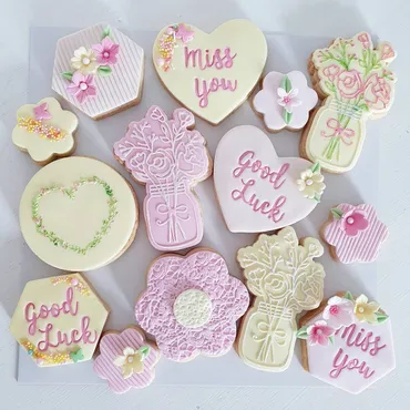 Blue and white baby shower iced biscuits with onesie, baby bottle, bib and baby feet designs
