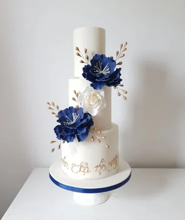 Three-tier semi-naked wedding cake with blush and white roses and gold Mr and Mrs topper