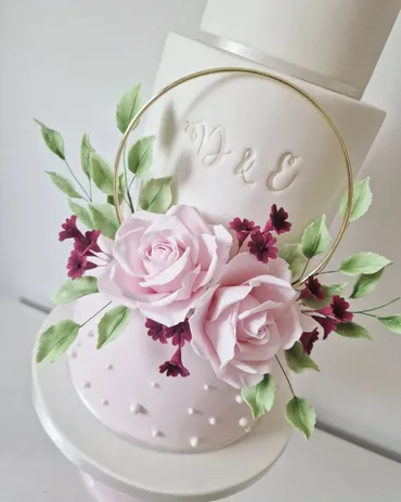 Two-tier wedding cake with bark texture bottom tier and white top tier with ivy and blue berry sugar flowers