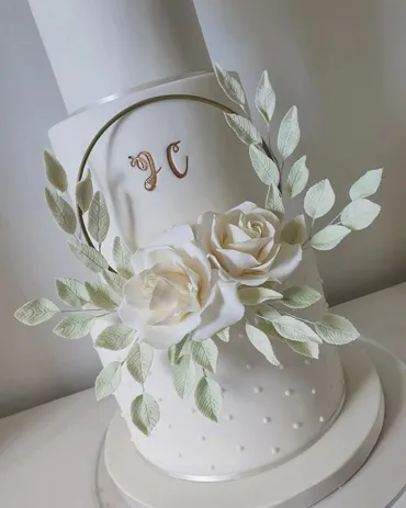 Four-tier white wedding cake with blush pink ombre top tier and large pink sugar roses