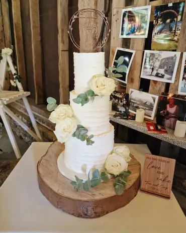 Four-tier ivory wedding cake with white and blush lisianthus flowers and gold Mr & Mrs Weapon topper