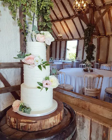 Four-tier white and deep pink ombre wedding cake with red and pink roses and gold leaf detail