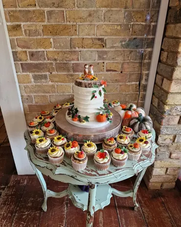 Autumn wedding cake with semi-naked tiers, pumpkins and sunflower cupcakes on a vintage table