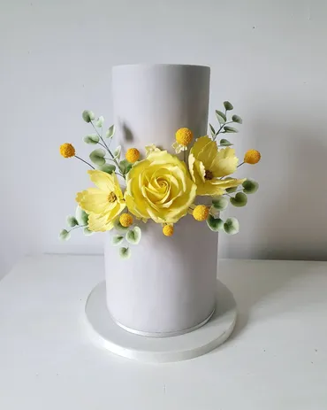 Three-tier white wedding cake with pink blossom ball topper and floral heart detail