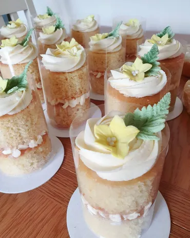 Four-tier white wedding cake with cascading pink roses on a wooden log stand
