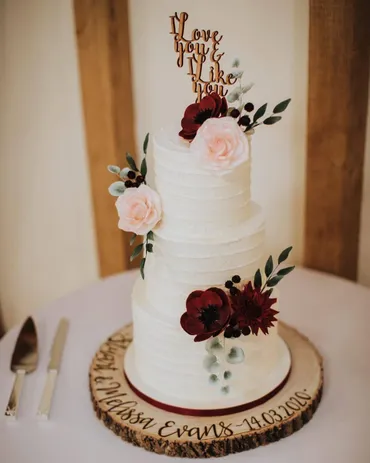 Three-tier blush pink wedding cake with cascading large sugar roses and ribbon detail on a pink cake stand