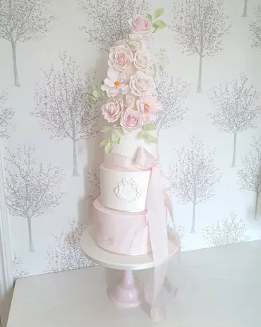 Three-tier white textured wedding cake with burgundy and blush sugar flowers and I Love You I Like You wooden topper on a wooden log stand