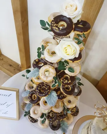 Three-tier sage green watercolour wedding cake with cascading white sugar roses and silk ribbon on a gold stand