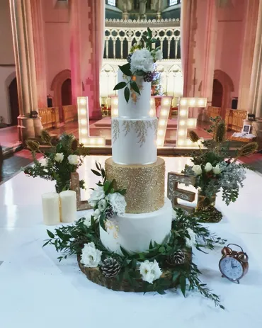 Bride and groom cutting a two-tier white wedding cake with blush roses and gypsophila in a garden setting