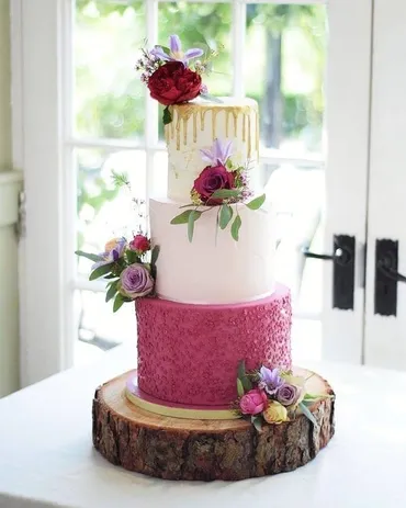 Two-tier sage green ombre wedding cake with silk ribbon and blush roses on a white stand in a garden setting
