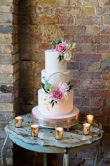 Four-tier wedding cake with fuchsia pink and gold tier, white tiers and white anemone sugar flowers