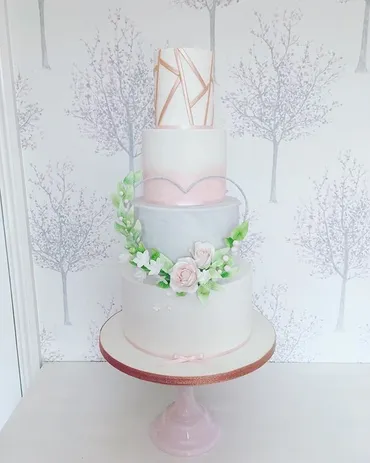 Three-tier grey and white wedding cake with gold art deco textured tier and white orchid sugar flowers on a gold stand