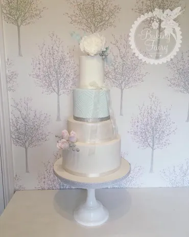 Five-tier white and rose gold wedding cake with blush sugar roses and silver lace detail