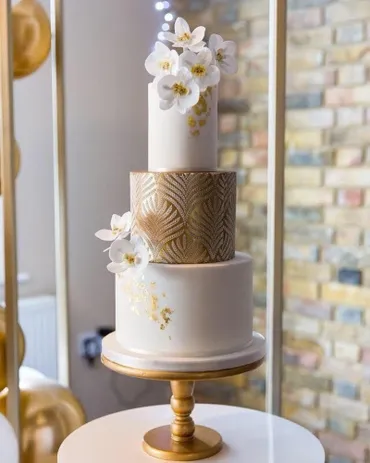 Four-tier pink ombre and geometric wedding cake with lily of the valley and blush roses on a pink stand